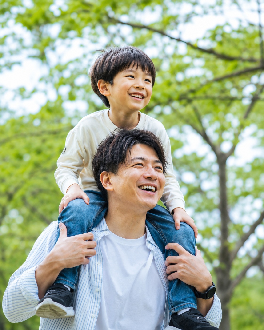 緑の公園で肩車を楽しむ父親と息子